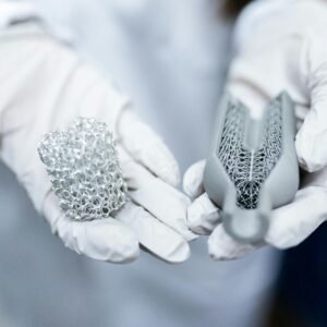 Laboratory setting showing gloved hands holding innovative 3D printed metal structures.